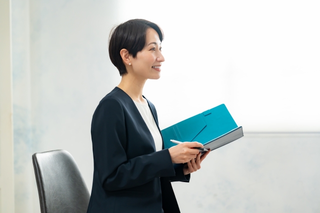 ファイルを手に、人の話を聞いている女性