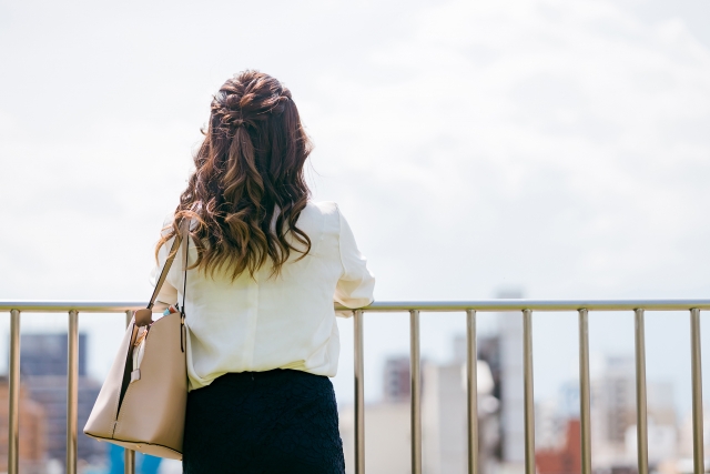 屋上で物思いにふける女性の後ろ姿
